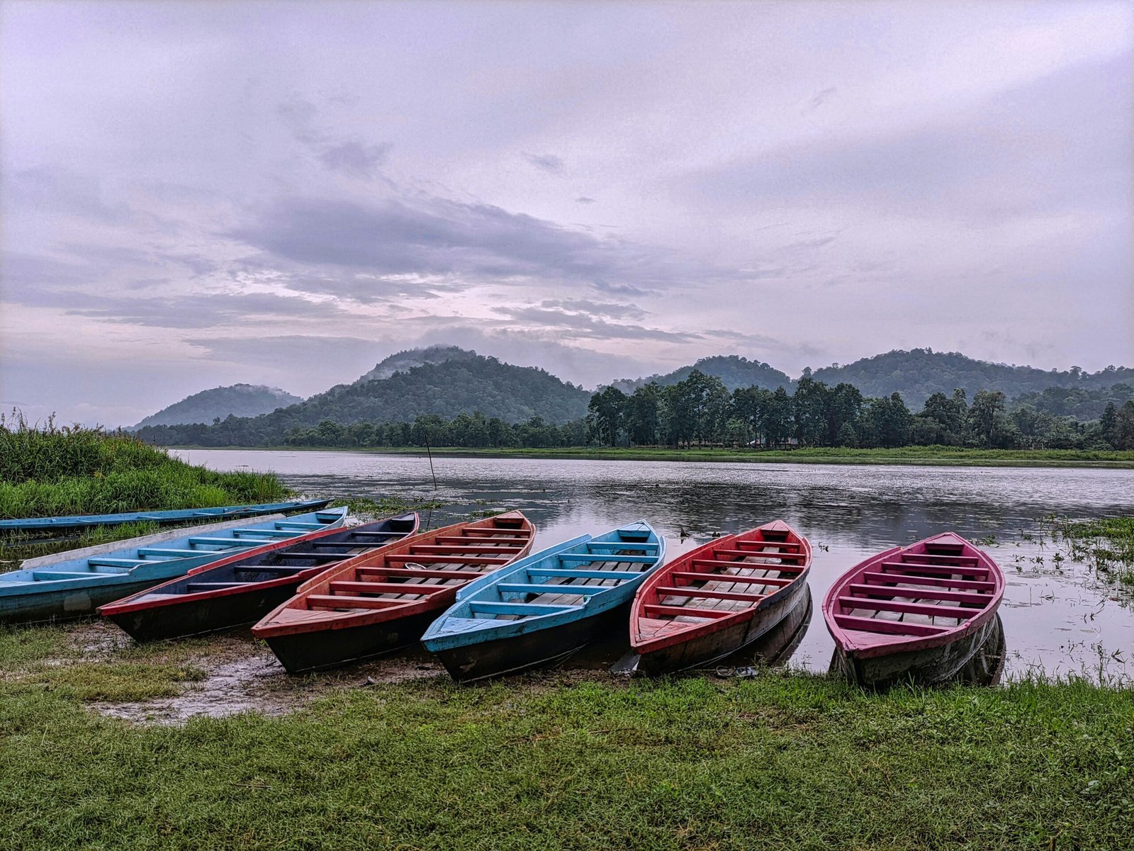 a group of boats sit on the shore of a lake